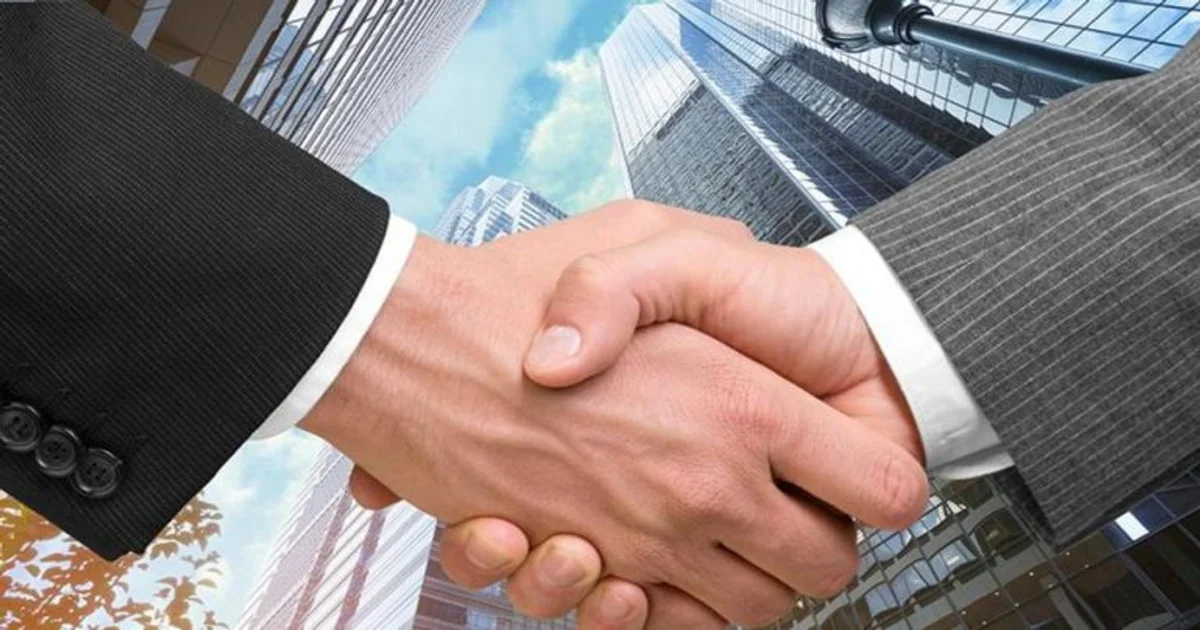 صورة توضيحية عن أسباب الدمج والاستحواذ بين الشركات تظهر شراكة تجارية أمام أبراج ومقار شركات حديثة