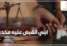 ابني اتقبض عليه مخدرات مع ميزان العدالة ومتهم مقيد اليدين في خلفية قانونية توضح خطورة قضايا المخدرات وأهمية التحرك القانوني السريع.