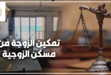 امرأة حاضنة تحمل أوراقًا رسمية أمام باب مسكن الزوجية مع طفلتها في دعوى تمكين الزوجة من مسكن الزوجية.